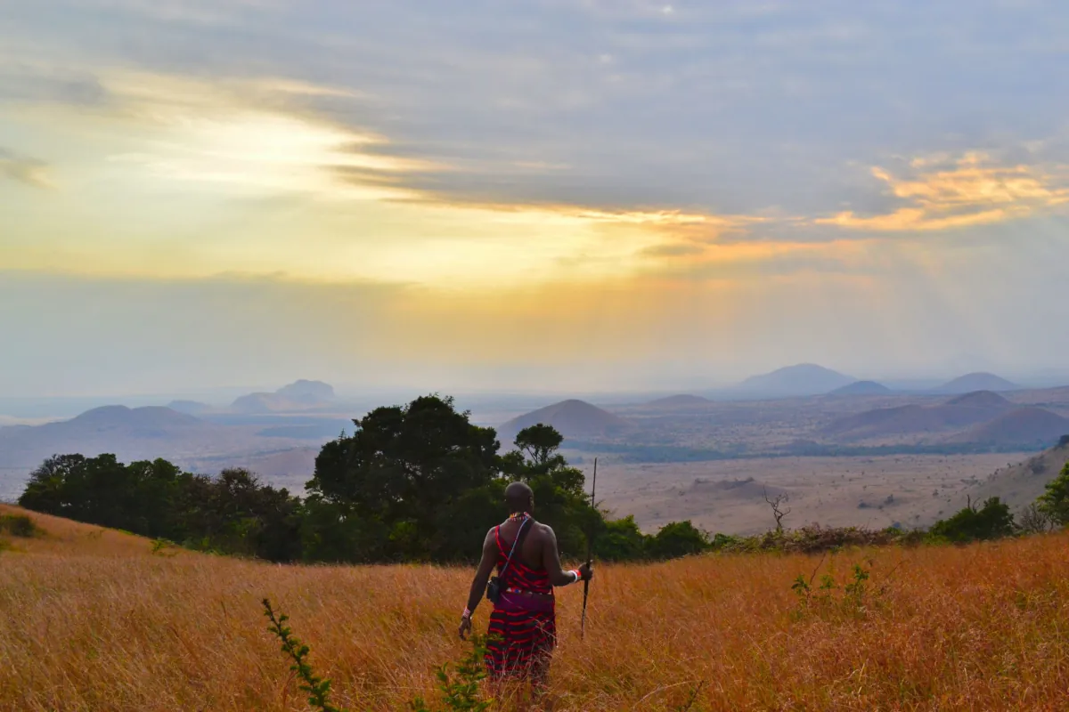 Hombre de una tribu pre-neolítica contemplando un paisaje natural al atardecer, base teórica para el estudio de la salud