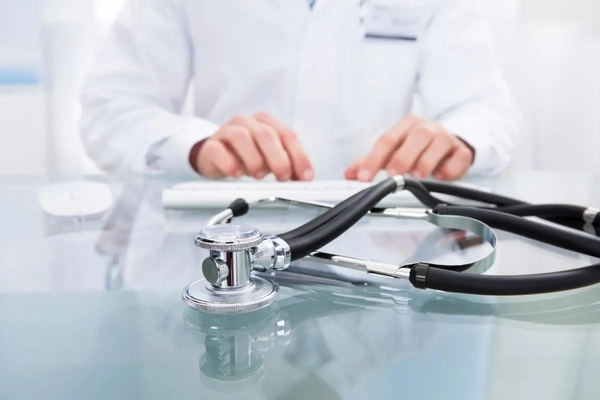 Salud óptima vs. valores bioquímicos normales Estetoscopio en primer plano con un médico al fondo, representando la diferencia entre valores normales y salud óptima