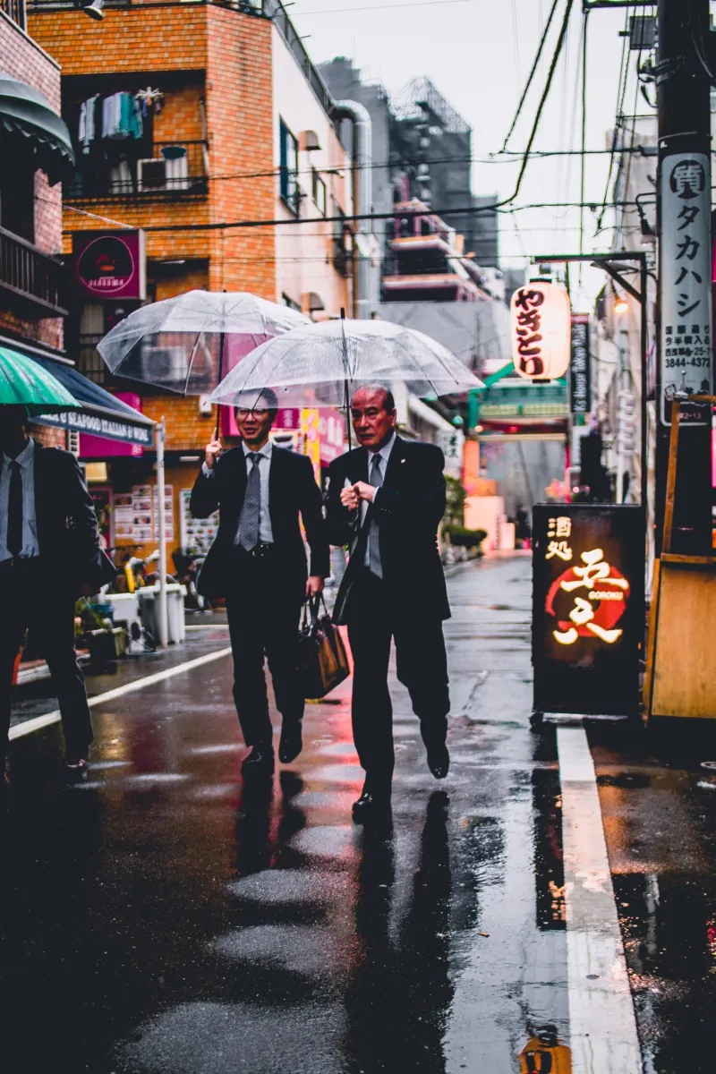 Ejecutivos con paraguas en Japón representando el entorno laboral.