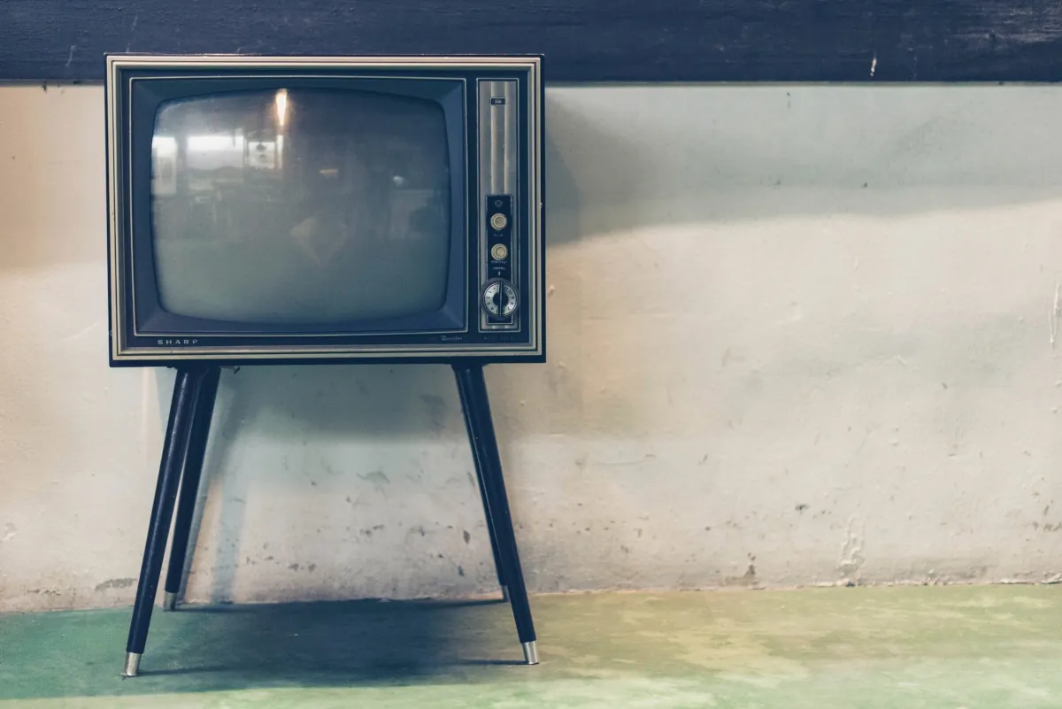 Televisor antiguo de tubo sobre patas metálicas, representando el impacto de los medios en la salud pública.
