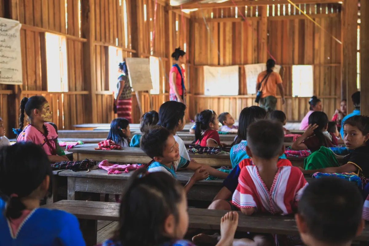 Grupo de niños en una escuela rural de madera, ilustrando cómo el entorno social y educativo influye en la salud.