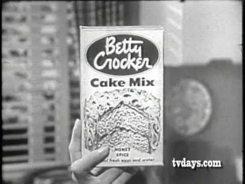 Anuncio antiguo en blanco y negro que muestra una mano sosteniendo una caja de mezcla para pasteles de la marca Betty Crocker.