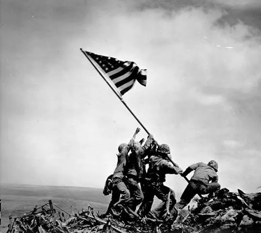 Fotografía histórica de soldados alzando la bandera de Estados Unidos en Iwo Jima durante la Segunda Guerra Mundial, representando la lucha y la victoria en el ámbito de la salud.