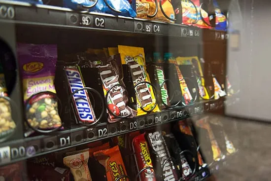 Interior de una máquina expendedora con snacks ultraprocesados, chocolatinas y productos azucarados, utilizada para ilustrar la disponibilidad de comida poco saludable y su impacto en el ayuno intermitente.