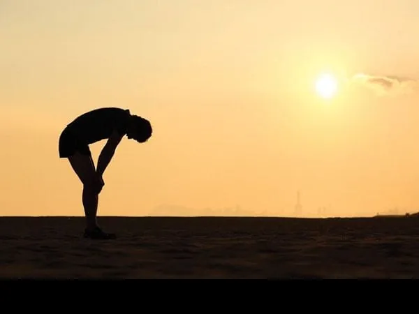 Silueta de una persona cansada durante un entrenamiento al atardecer, representando el esfuerzo físico y la gestión de la fatiga para no abandonar el ejercicio.