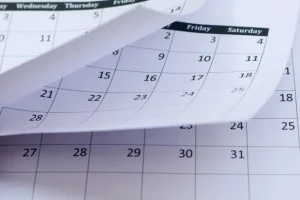 Primer plano de una mano pasando la página de un calendario de pared blanco